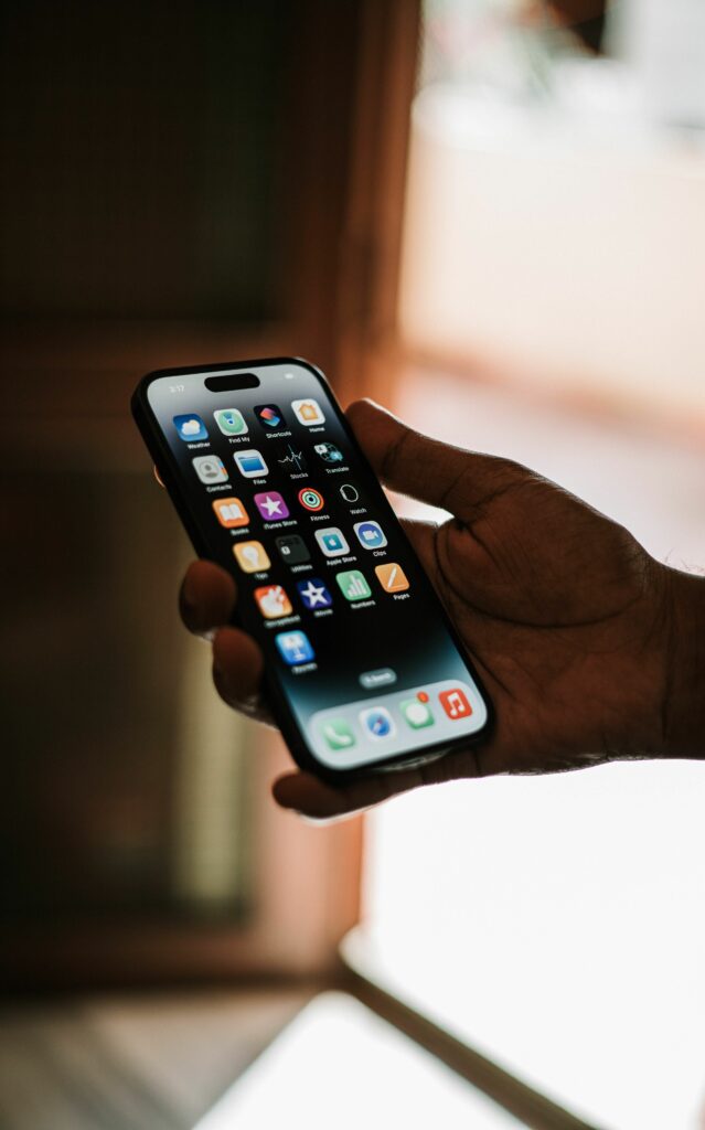 Close-up of a hand holding a smartphone with apps on the screen in focus.